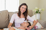 Happy man resting on womans lap on couch