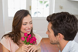 Woman looking at man with flowers at home