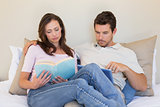 Concentrated Couple with digital tablet and book at home