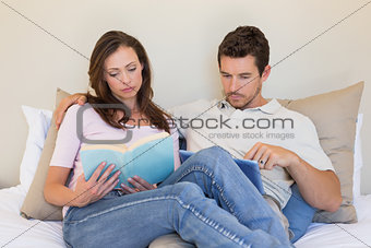 Concentrated Couple with digital tablet and book at home