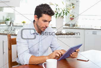 Concentrated man using digital tablet in kitchen