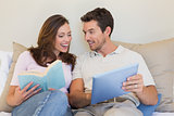 Happy couple with laptop and book on couch