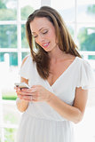 Smiling woman text messaging in home