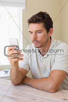 Concentrated man text messaging in home