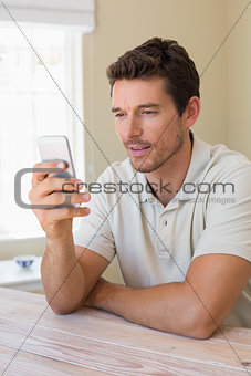 Concentrated man text messaging in home