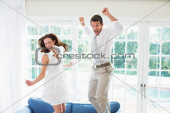 Cheerful young couple jumping on couch