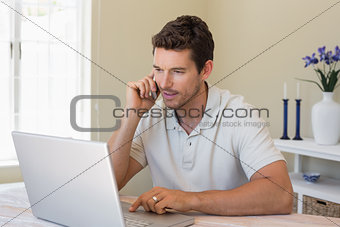 Man using laptop and mobile phone at home