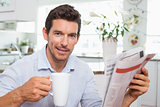 Man with newspaper and coffee cup at home