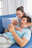 Loving couple with digital tablet in living room at home