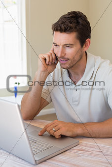Man using laptop and mobile phone at home