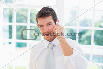 Smiling businessman using mobile phone at home