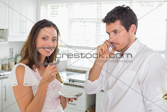 Woman drinking coffee while man using cellphone at home