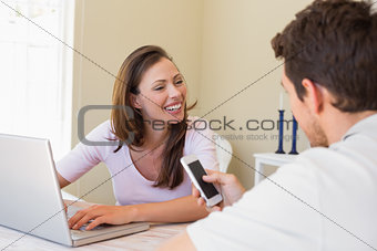 Couple using laptop and cellphone at home