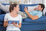 Couple using digital tablet and cellphone in living room