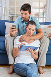 Couple using digital tablet and cellphone in living room