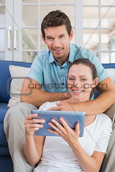 Happy couple using digital tablet on couch