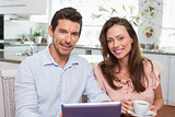 Couple using digital tablet while having coffee at home
