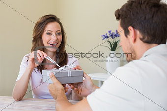 Man giving happy woman a gift box at home