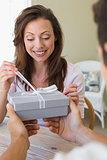 Cropped man giving woman a gift box at home