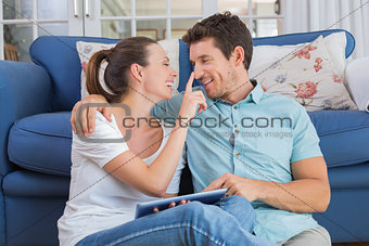 Happy couple using digital tablet in living room