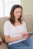 Smiling young woman text messaging in living room