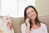 Smiling woman using mobile phone in living room