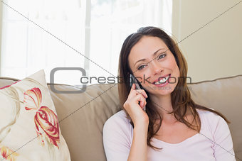 Smiling woman using mobile phone in living room