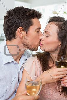 Loving couple with wine glasses kissing at home