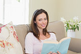 Happy woman reading book in living room