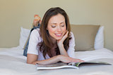 Smiling relaxed woman reading a book in bed
