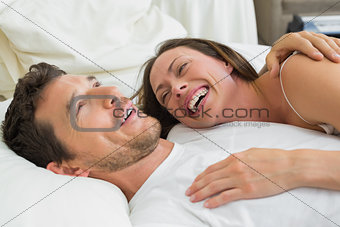 Cheerful couple lying together in bed