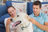Relaxed couple with wine glasses and pet dog in living room