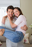 Smiling man carrying woman at home