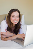 Smiling relaxed woman using laptop in bed