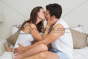 Loving young couple kissing in bed