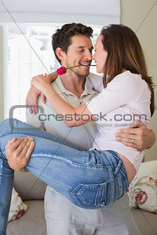 Smiling man carrying woman at home