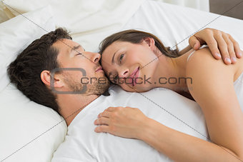 Loving young couple lying in bed at home