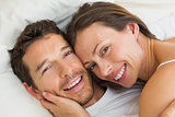 Happy young couple lying together in bed