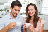 Happy young couple with coffee cups in kitchen