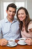Happy couple with coffee cups at home