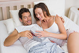 Couple with gift box lying together in bed