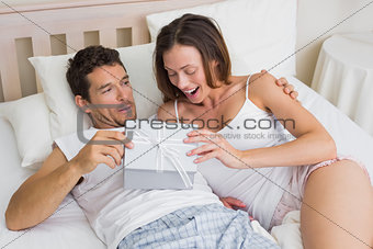 Couple with gift box lying together in bed