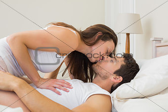 Relaxed young couple kissing in bed