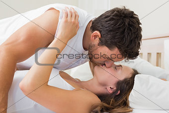 Relaxed young couple kissing in bed