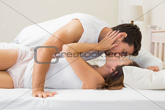 Side view of a relaxed couple kissing in bed