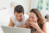 Smiling couple using laptop in bed