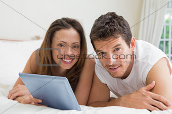 Couple using digital tablet in bed