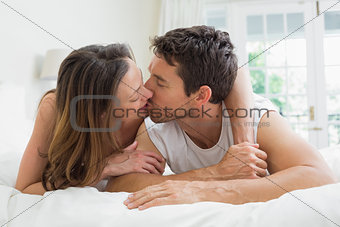 Relaxed couple kissing in bed
