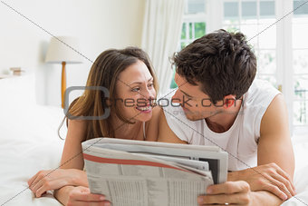 Relaxed couple reading newspaper in bed