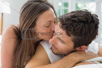 Young woman kissing man in bed